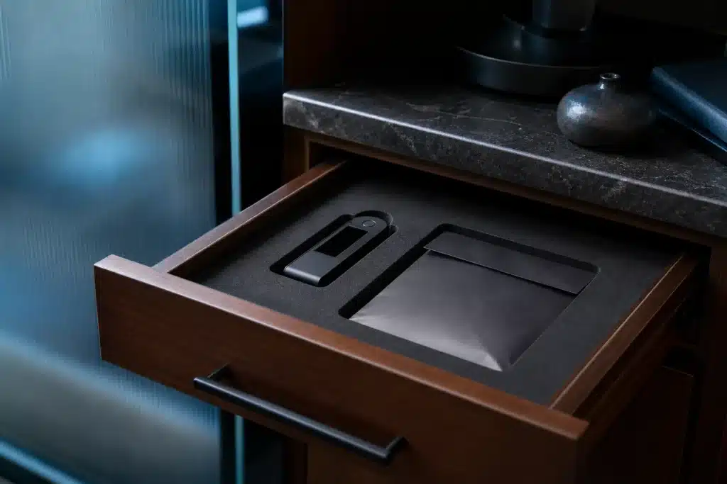 Illustrative hardware wallet in a protective case beside a sealed backup envelope