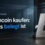Litecoin kaufen: Metallsymbol auf einem Schreibtisch neben geschlossenen Rechercheunterlagen